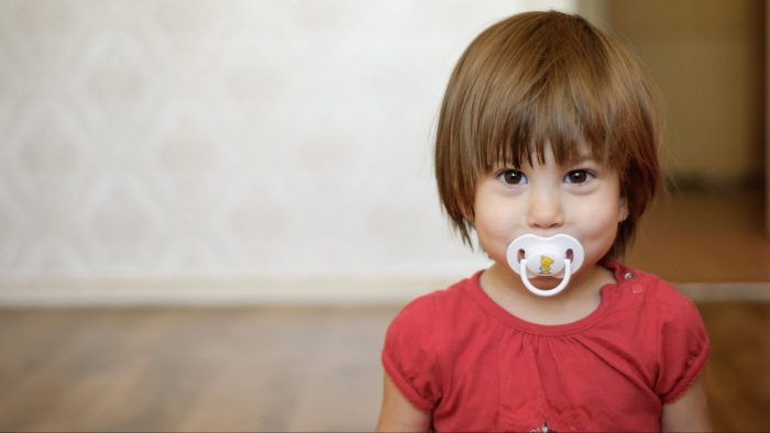 young girl with pacifier in mouth